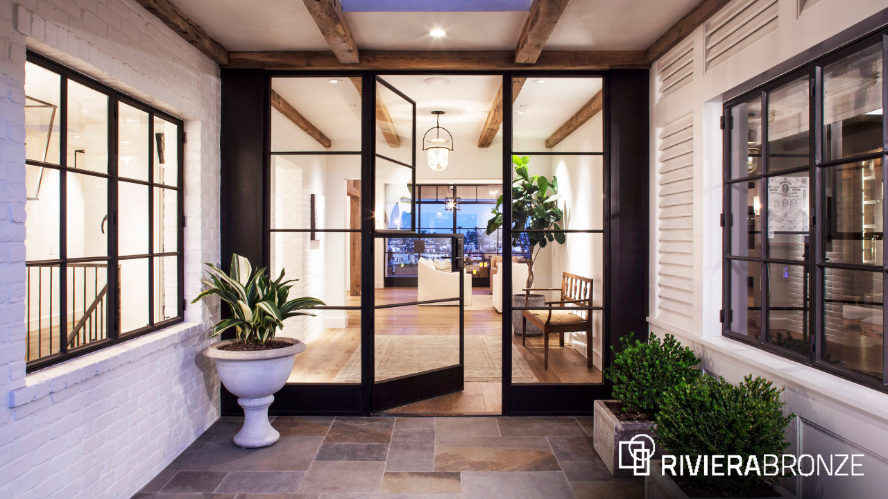 Custom Steel Doors for Seamless Indoor–Outdoor Living – Riviera Bronze Luxury indoor–outdoor living space featuring custom steel doors with slim sightlines, connecting a refined interior to an exterior courtyard with seamless architectural flow.